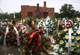 Gedenkkränze stehen vor einem Backsteindenkmal